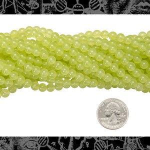 May include: A strand of light green jade beads, approximately 6mm in diameter, with a US quarter for scale.