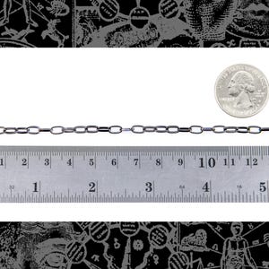 May include: A silver chain necklace with a box chain design. The chain is measured against a ruler, showing it is approximately 10 inches long. A US quarter is shown for scale.