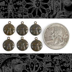 May include: Six antique bronze-colored metal charms shaped like a crescent moon with a human face embossed on the front. The charms are approximately the size of a US quarter.