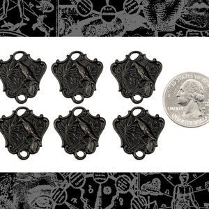 May include: Six antique-style metal charms featuring a bird perched on a branch. The charms are in the shape of a shield with a decorative border. Each charm has a loop at the top for attaching to a necklace or bracelet. A US quarter is included for size reference.