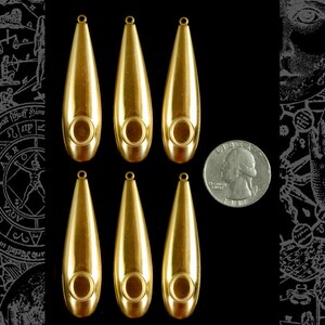 Puede incluir: Seis colgantes de metal de color dorado en forma de lágrima con un agujero en el centro. Los colgantes son aproximadamente del tamaño de una moneda de 25 centavos de dólar estadounidense.