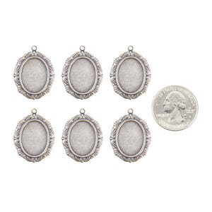 May include: Six silver-toned oval-shaped pendant trays with ornate edges. The trays are approximately the size of a US quarter.