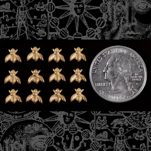 May include: A close-up of 12 gold bee charms arranged in a grid pattern. The charms are about the size of a US quarter.