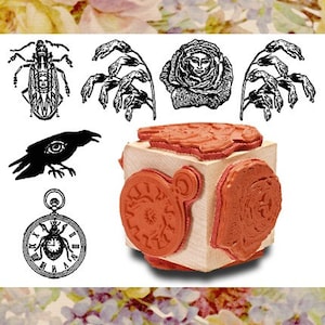 May include: A wooden block with four different rubber stamps. The stamps feature a clock, a crow, a rose, and a beetle. The stamps are designed for crafting and scrapbooking.