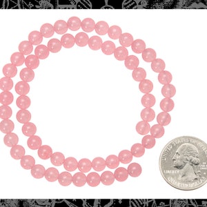 Peut inclure: Un collier de perles de quartz rose, d'environ 46 cm de long, avec un quart de dollar am&eacute;ricain pour l'&eacute;chelle.