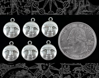 May include: Six silver-toned metal charms shaped like a crescent moon with a face on each. The charms have a slightly textured surface. The charms are arranged in two rows of three. A silver-toned quarter is also in the image.