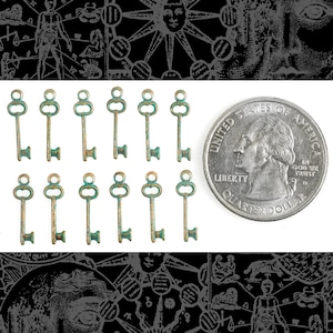 May include: A set of 12 antique-style key charms, each measuring approximately 1 inch in length. The keys are made of metal and have a distressed, aged finish with a green patina. The keys are arranged in two rows of six, with a US quarter dollar coin for scale.