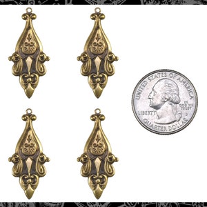 May include: Four ornate gold-toned metal pendant charms with intricate designs. Each charm features a teardrop shape with a pointed bottom and a decorative top. The charms are approximately the size of a US quarter.