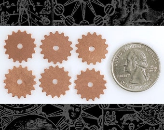 May include: Six copper-colored gear-shaped metal charms with a hole in the center. The charms are arranged in two rows of three. A US quarter is included for size comparison.