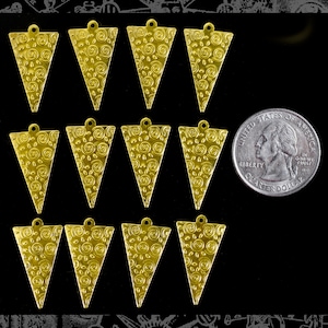 Puede incluir: Doce abalorios de metal de forma triangular dorada con un patrón de espiral. Los abalorios son aproximadamente del tamaño de una moneda de 25 centavos de dólar estadounidense.