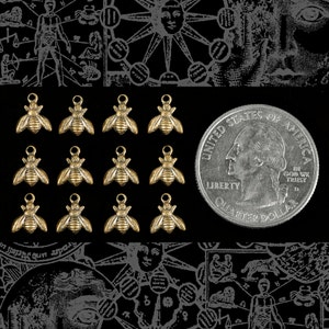 May include: Twelve gold-toned bee charms with a textured surface. The charms are arranged in four rows of three. A US quarter is included for size reference.