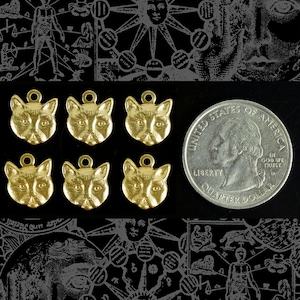 May include: Six gold-colored cat charm pendants, each with a detailed cat face design. The charms are approximately the size of a US quarter.