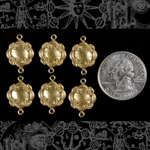 Könnte beinhalten: Sechs goldfarbene, verzierte Verbindungsanhänger mit einem Viertel zur Größenvergleich. Jeder Anhänger hat ein zentrales, leicht erhabenes, ovales Design, das von einer blütenartigen Bordüre umgeben ist. Die Anhänger haben kleine Schlaufen oben und unten zur Befestigung.