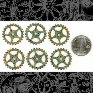 Może przedstawiać: Sześć zielonych i złotych metalowych kół zębatych z ozdobnym wzorem. Koła zębate są ułożone w dwóch rzędach po trzy. Do porównania rozmiarów dołączono amerykańską monetę 25 centów.