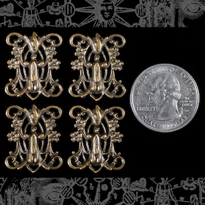May include: Four antique gold-toned metal decorative embellishments with a floral design. The embellishments are about the size of a US quarter.