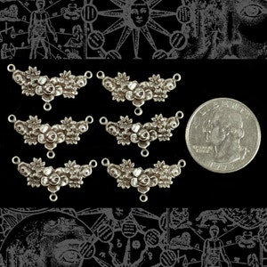 May include: Six silver-toned metal charms in the shape of a floral garland with a double loop at the top. The charms are approximately the size of a US quarter.