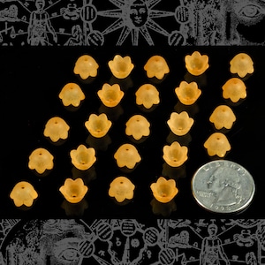 May include: A collection of 20 amber-colored glass beads, each shaped like a flower with five petals. The beads are arranged in a triangular pattern on a black surface.