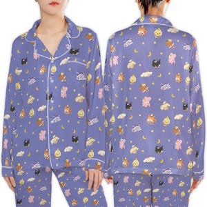 May include: A two-piece pajama set in a periwinkle blue color, featuring a repeating pattern of cartoon animals, moons, clouds, and stars. The long-sleeved top has a button-down front with white trim, and the matching pants complete the set.