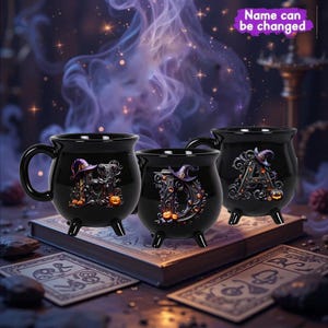 May include: Three black cauldron-shaped mugs with handles and three small legs. Each mug features a letter, a witch hat, and pumpkins. The text "Name can be changed" is visible in the background. The mugs are on a book.