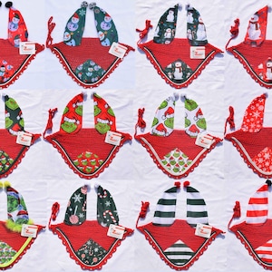 May include: A collection of red Christmas horse bonnets with various festive patterns. Designs include snowmen, Grinches, snowflakes, and candy canes. Each bonnet has a crocheted red base and ear coverings with matching holiday prints. The bonnets are designed for horses.