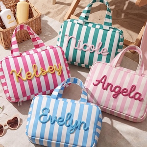 May include: Four rectangular zippered travel bags with two top handles, each featuring vertical stripes and a name embroidered in rope-style lettering. The bags are pink and white, teal and white, light pink and white, and blue and white.