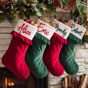 Puede incluir: Cuatro calcetines navideños de terciopelo en colores alternos rojo y verde, cada uno con un puño blanco con ribete de volantes. Los puños están bordados con los nombres Alice, Eric, Mandy y Robert en letras cursivas rojas o verdes.