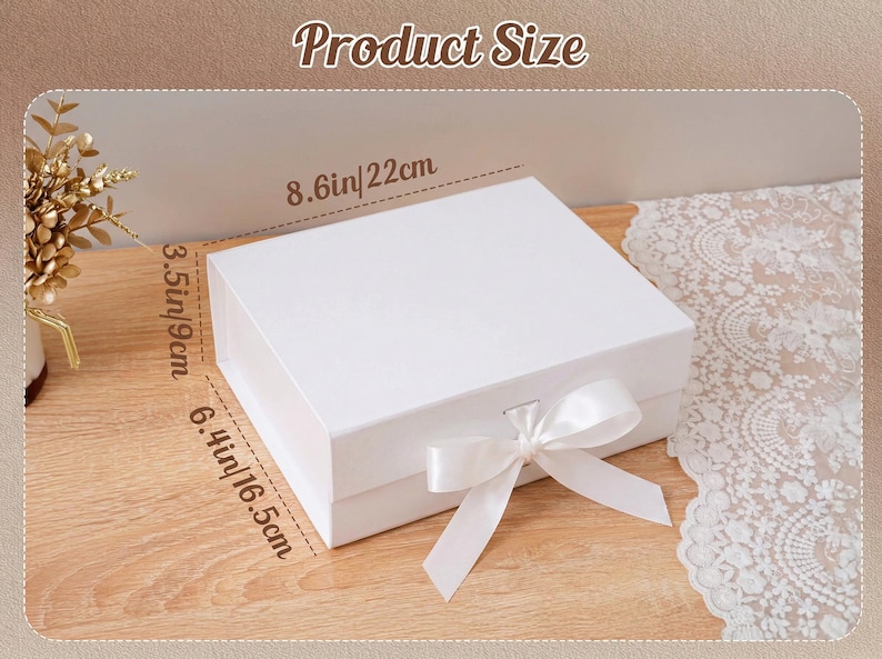 Peut inclure: Une bo&icirc;te cadeau blanche avec un n&oelig;ud en ruban de satin. La bo&icirc;te mesure 22 cm de large, 16,5 cm de long et 9 cm de haut. Le texte "Product Size" est en haut de l'image.
