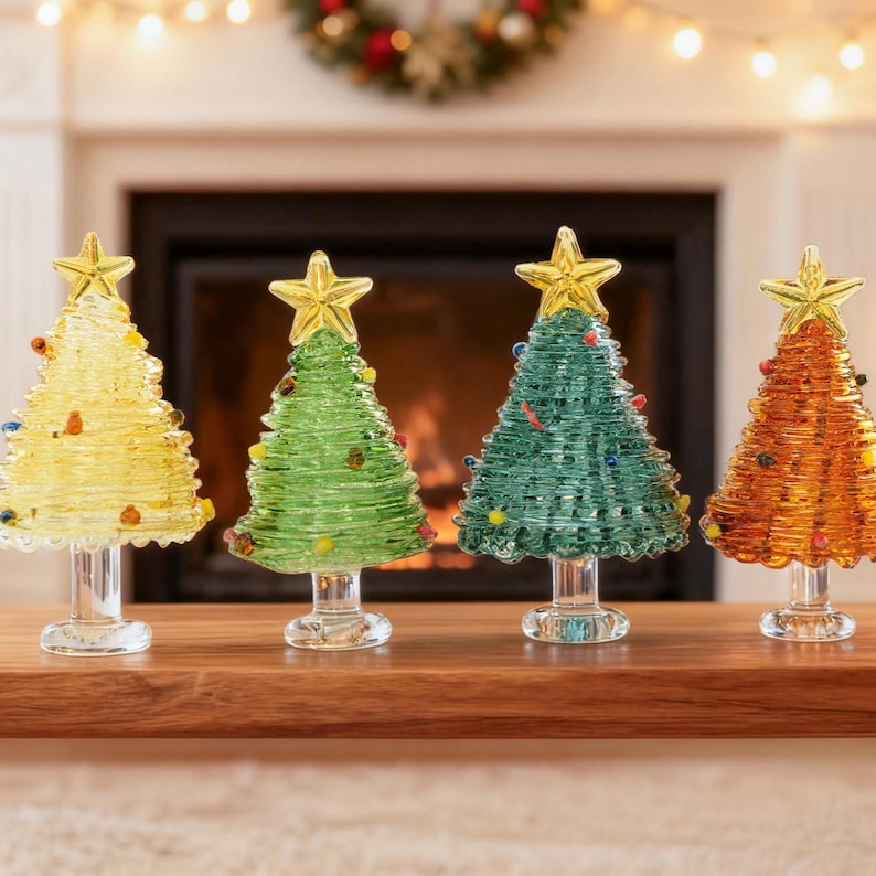 May include: Four glass Christmas tree figurines standing on clear pedestals. Each tree features a coiled glass design in yellow, light green, teal, and amber, topped with a yellow star and decorated with small, colorful glass beads.
