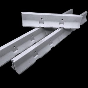 May include: Three light gray concrete barriers with a linear, elongated shape. Each barrier features a distinct L-shaped profile with a flat base, a vertical wall section, and two circular holes positioned along the upper edge of the wall.