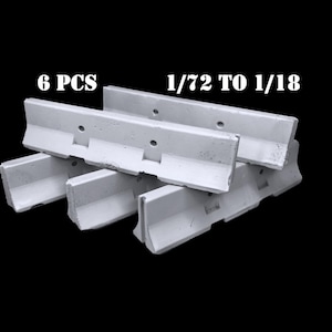 May include: A set of 6 white concrete-style jersey barriers featuring a sloped profile and two circular holes along the top edge. The text 6 PCS and 1/72 TO 1/18 is printed in white above the barriers, which are arranged in a stacked formation.