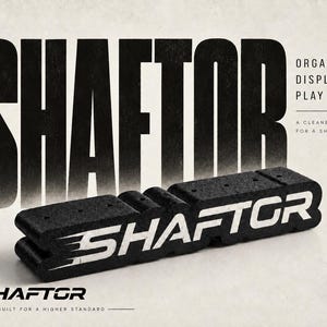 Könnte beinhalten: Ein schwarzer, rechteckiger und texturierter Schaumstoff-Organizerblock mit dem weißen Schriftzug SHAFTOR an der Seite. Im Hintergrund ist der große schwarze Schriftzug SHAFTOR sowie die Phrasen ORGANIZE. DISPLAY. PLAY MORE. und BUILT FOR A HIGHER STANDARD zu sehen.