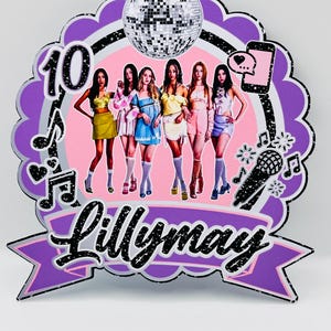 May include: A decorative cake topper featuring a scalloped purple border, a disco ball, a microphone, and a smartphone icon. The centre displays an image of six people standing in a row, with the number 10 and the name Lillymay in black script.
