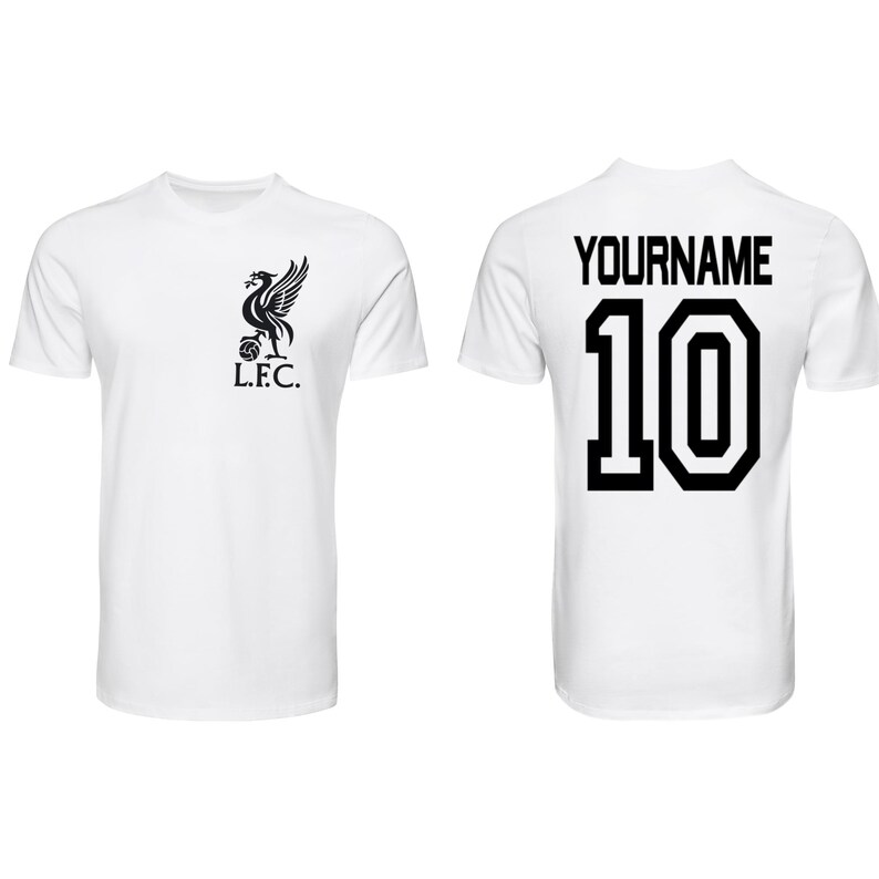 May include: White t-shirt featuring the Liverpool Football Club emblem on the front and a personalized name and number 10 on the back. The emblem is a black bird with the letters L.F.C. below it. The text "YOURNAME" is above the number.