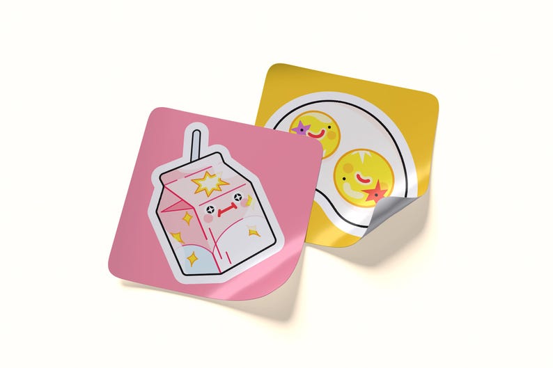 May include: Two square stickers with rounded corners. One sticker is pink and features a white milk carton with a smiling face and yellow star accents. The second sticker is yellow and displays a white plate with two fried eggs with faces.