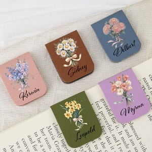 May include: Six floral magnetic bookmarks, each with a different flower bouquet design and a name printed below. The bookmarks are in various colours, including pink, brown, blue, green, and purple.