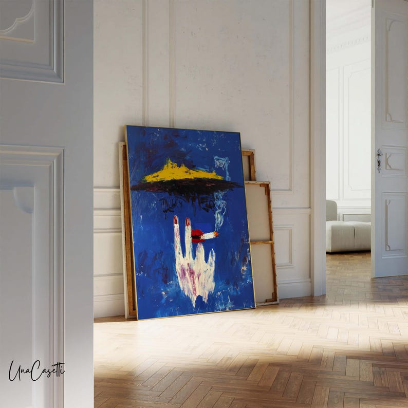 Pu&ograve; includere: Dipinto astratto su tela raffigurante una mano che tiene una sigaretta accesa su sfondo blu. L'opera d'arte include forme gialle e nere, con una mano bianca e unghie rosse. Il dipinto &egrave; appoggiato a un muro.