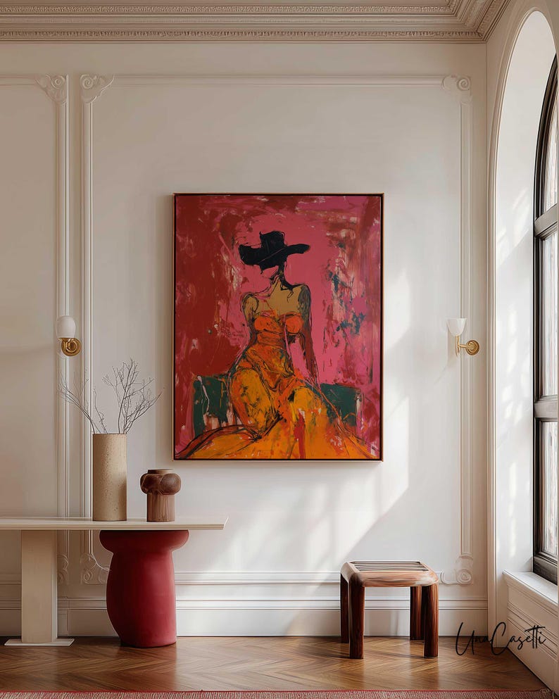 May include: Abstract painting of a figure in an orange dress and black hat against a red and pink background. The artwork is framed in a dark brown frame. The room features a console table, a red pedestal, and a wooden stool.