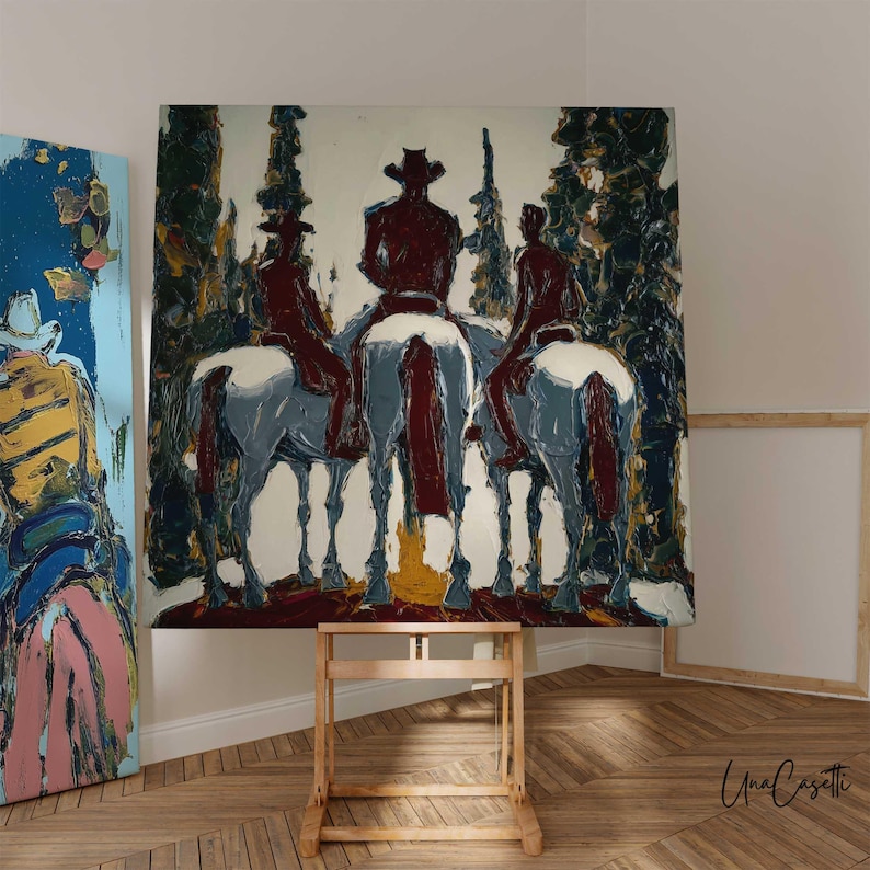 Puede incluir: Una pintura al &oacute;leo que representa a tres jinetes a caballo en un bosque. Las figuras son rojas, con caballos blancos y un fondo de &aacute;rboles verdes y marrones. La obra de arte se exhibe en un caballete de madera.