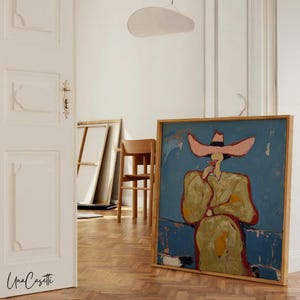 K&ouml;nnte beinhalten: Abstrakte Malerei in einem Holzrahmen, die eine Figur mit gro&szlig;em rosa Hut und gelbem Mantel vor blauem Hintergrund zeigt. Das Kunstwerk wird in einem Raum mit Holzboden und wei&szlig;en W&auml;nden ausgestellt.