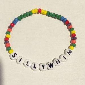May include: A colorful beaded bracelet with the word "SILLY WHIM" spelled out in white beads.