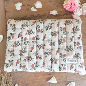 Peut inclure: Pochette matelassée crème avec un motif floral corail et gris. La pochette a une fermeture éclair dorée et une petite étiquette « Elembel ». Le motif floral est uniformément réparti sur la surface.