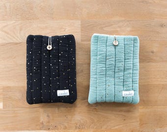 May include: Two rectangular quilted pouches, one black and one sage green, both featuring a gold speckled pattern. Each pouch has a vertical stitched design, a single wooden button closure with a white cord loop, and a small white label reading Elombee.
