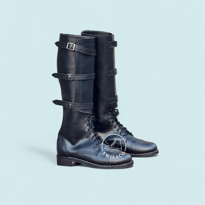 May include: A pair of black leather boots with multiple buckle straps and lace-up fronts. The tall boots have a classic design, suitable for various styles. The boots are displayed against a light blue background.