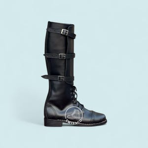 May include: Black leather knee-high boot with three buckle straps and lace-up closure. The boot features a cap toe design and a small heel. The brand logo is visible on the side of the boot.