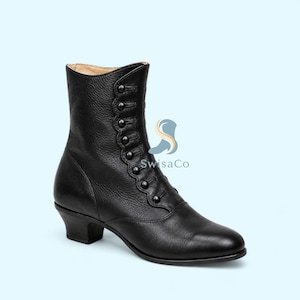 May include: A black leather ankle boot featuring a side button closure with a scalloped edge detail, a rounded toe, and a low block heel. The side of the boot displays a blue and orange logo graphic with the text SwisaCo printed in black.
