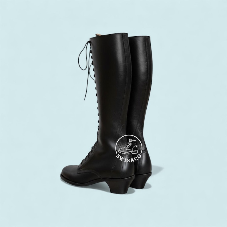 K&ouml;nnte beinhalten: Ein Paar schwarze, kniehohe Schn&uuml;rstiefel mit kleinem Absatz. Die Stiefel sind aus Leder und haben ein klassisches Design. Die Stiefel werden vor einem hellblauen Hintergrund pr&auml;sentiert.