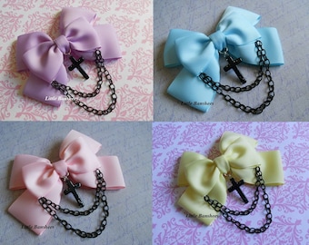 May include: Four different colored hair bows with a black cross charm and chain. The bows are lavender, light blue, pink, and yellow. The text "Little Banshees" is on each bow.