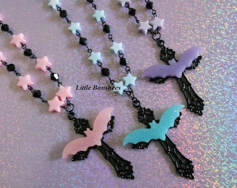 May include: Three necklaces with black chains and pastel colored star beads. Each necklace has a black cross pendant with a pastel colored bat charm.