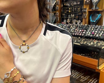 Puede incluir: Conjunto de joyas que incluye pendientes, un collar y pulseras. Los pendientes y el collar presentan un diseño circular con detalles dorados y plateados. Las pulseras tienen un diseño similar, con múltiples círculos de diferentes tamaños y colores.