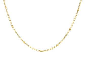 May include: A delicate gold-colored necklace with a curb chain design. The necklace features small, evenly spaced gold beads. The chain is a bright, shiny gold color, and the necklace is displayed against a white background.